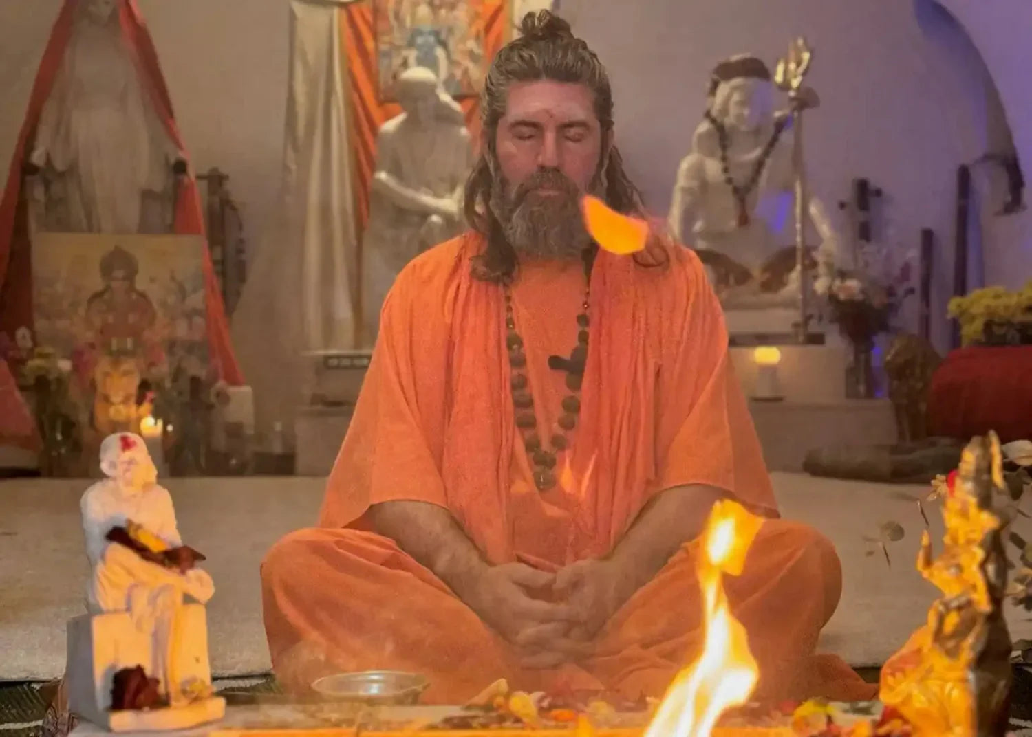 Meditating man in orange robe.
