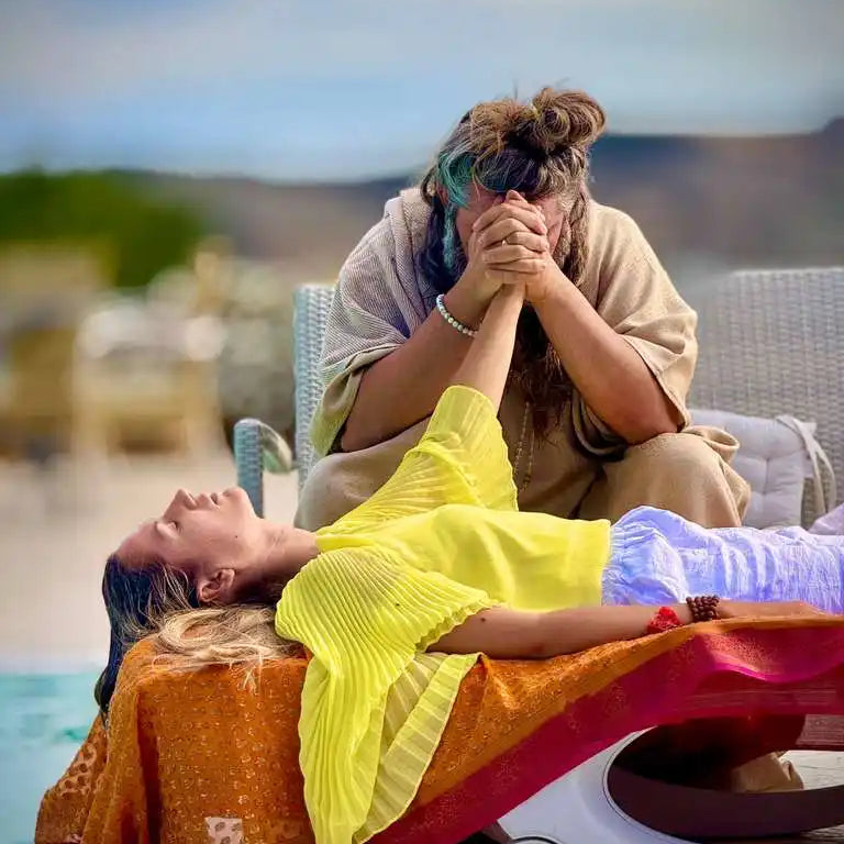 Two individuals engaged in a healing or spiritual practice, with one person lying down and the other holding their hand.
