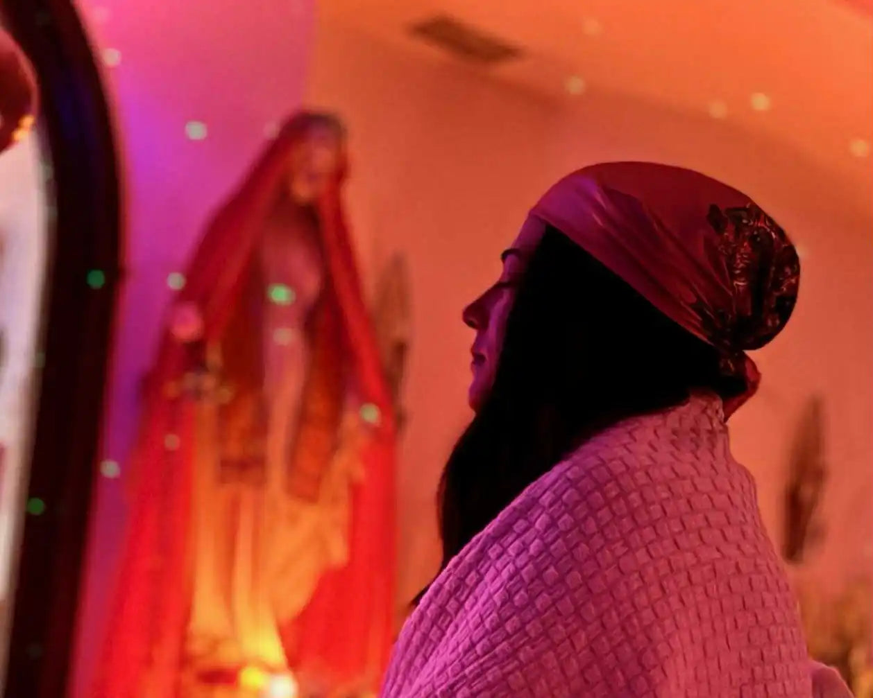 Woman wearing a headscarf and wrapped in a blanket, looking up.