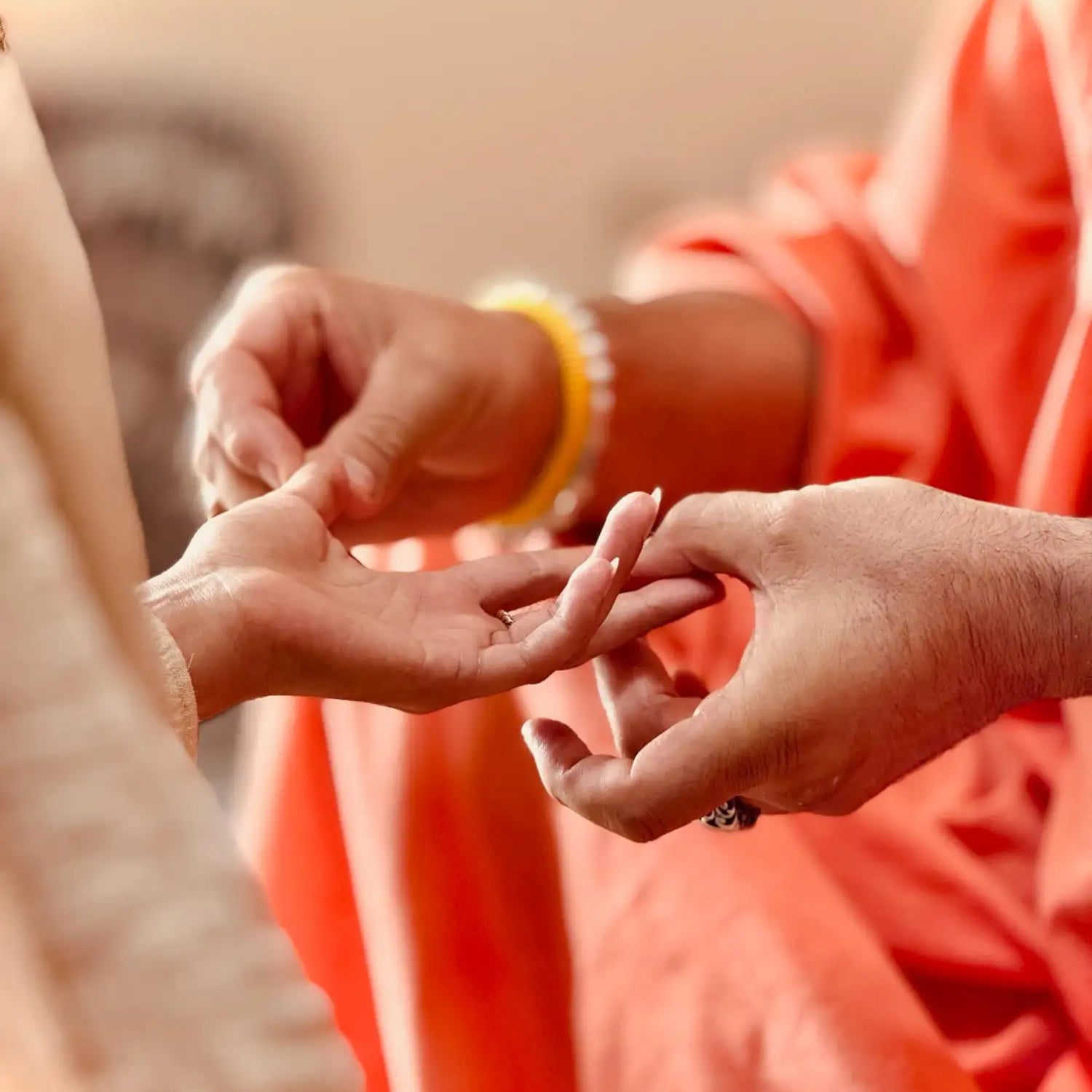 A delicate gold ring with a simple, elegant design is being placed on someone’s finger.