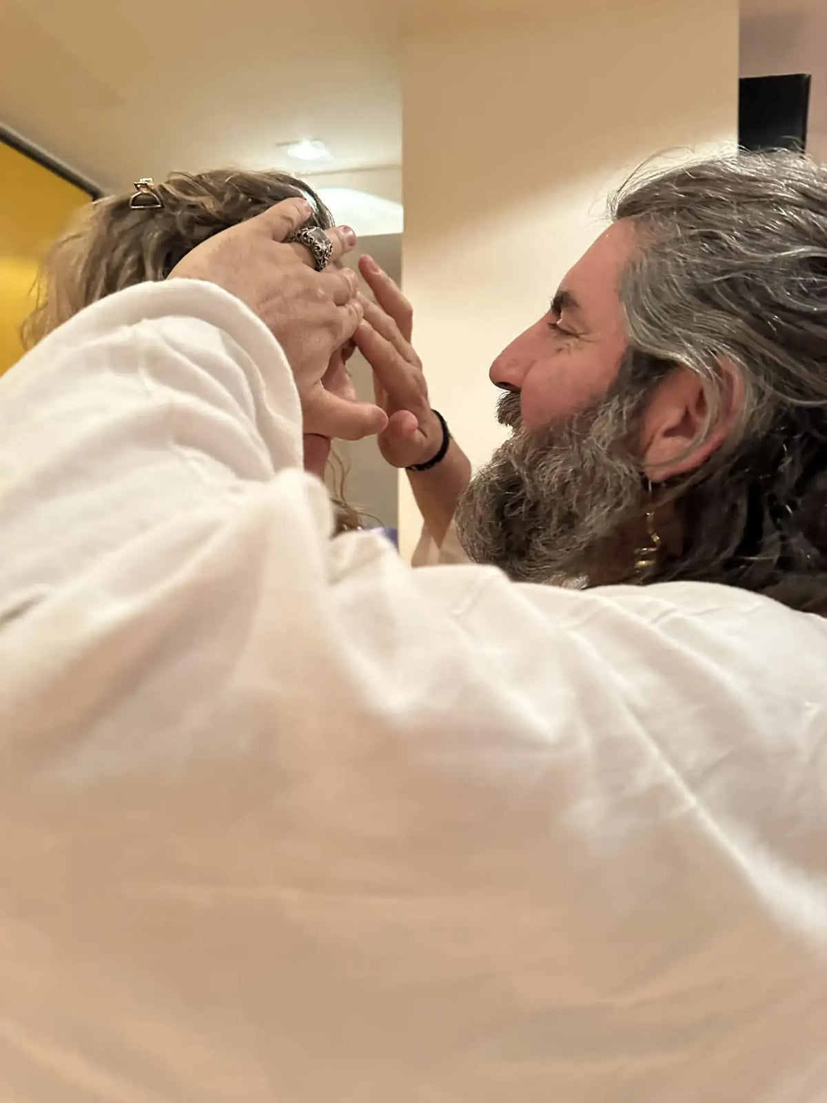 A man with long gray hair and a beard, wearing a white robe.