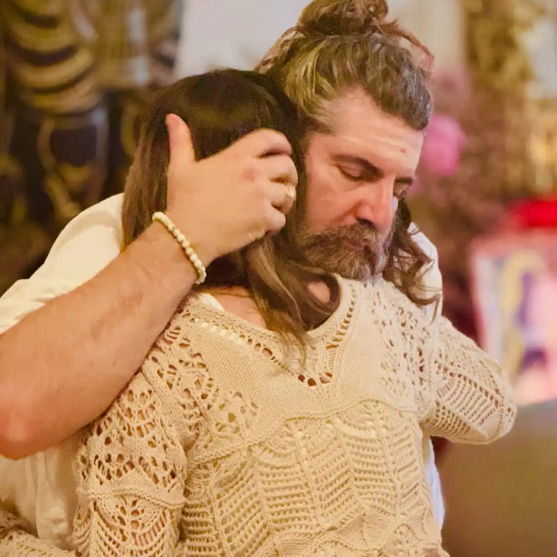 Man with long hair and beard hugging a woman.