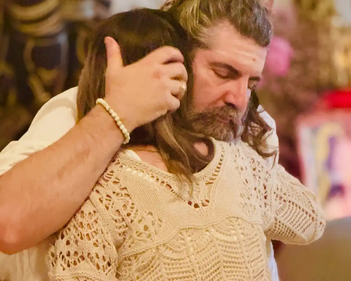 Man with long hair and beard hugging a woman.