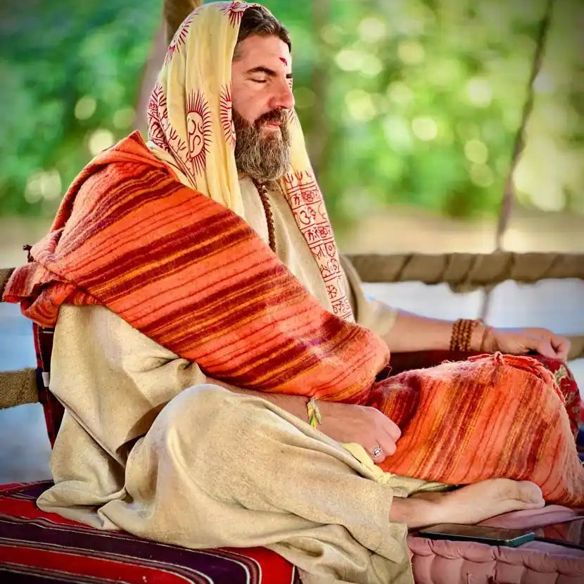 A man meditating in traditional Indian attire.