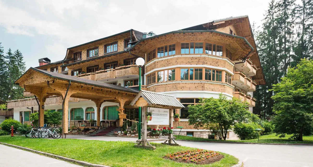 A multi-story wooden building with a curved facade, green-framed windows, and balconies.
