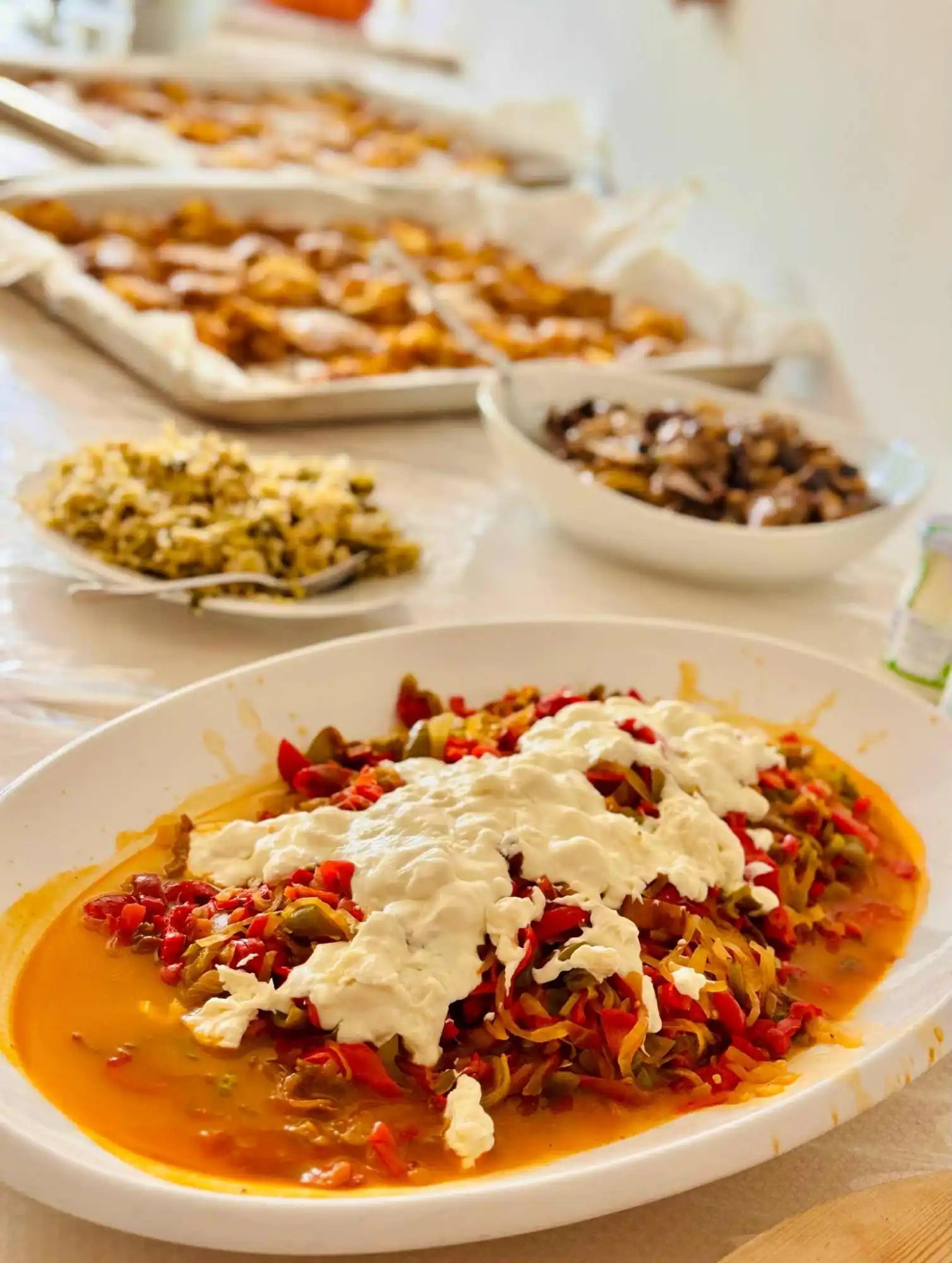 A large platter of stewed peppers with a dollop of fresh cheese.