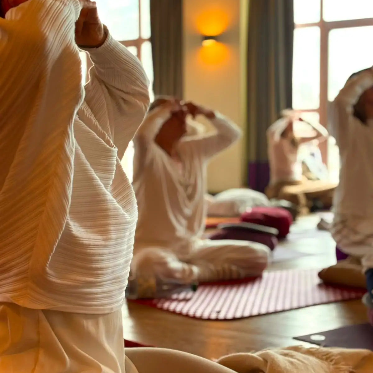 A soft, off-white ribbed knit long-sleeved top worn by a person in a yoga studio.