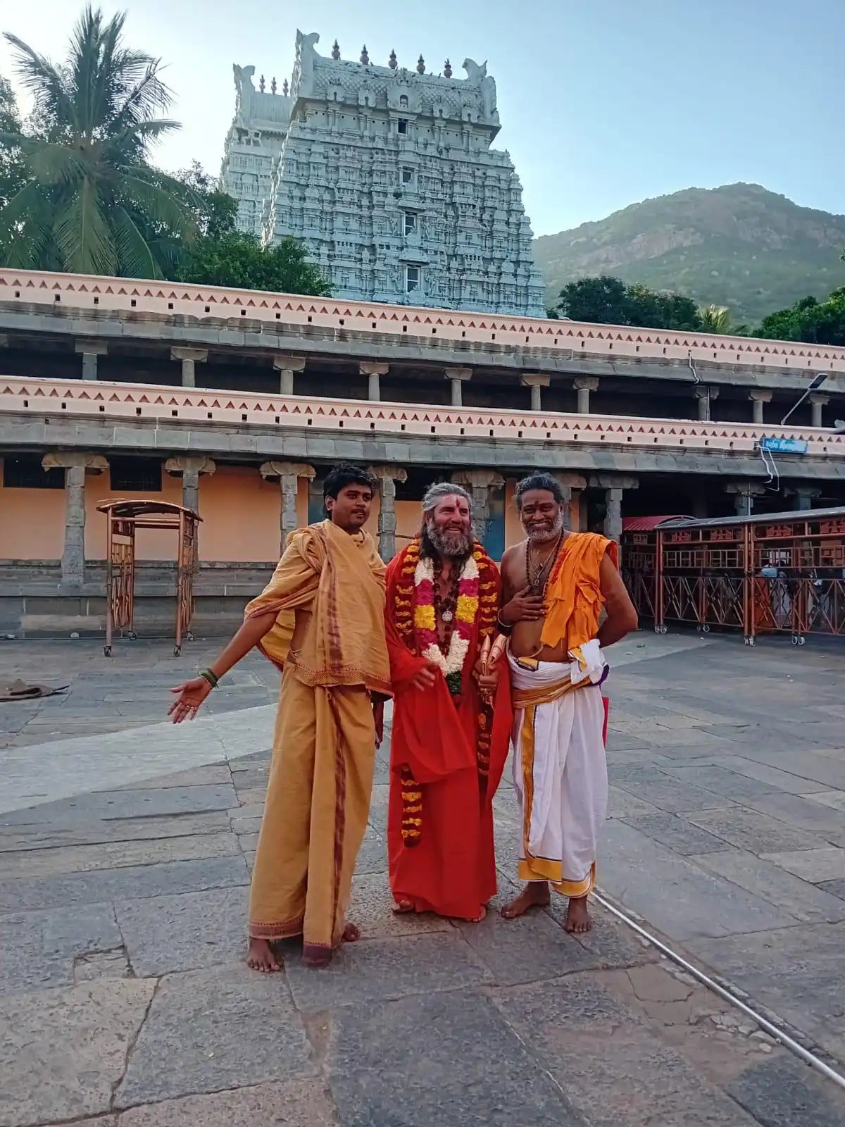 Three men in traditional Indian attire posing in front of a temple.
