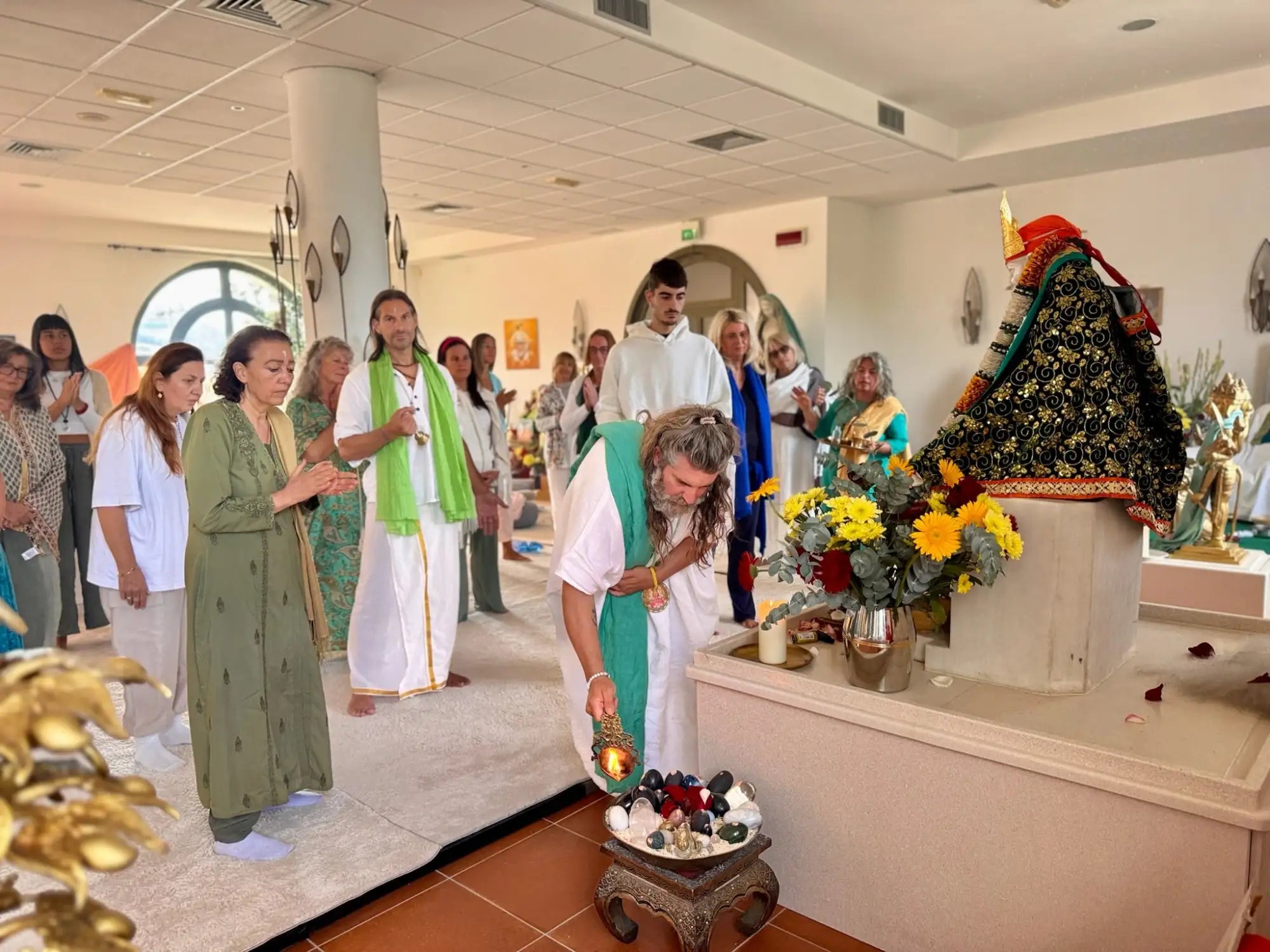 White ceramic bowl with floral arrangement and lit candle.