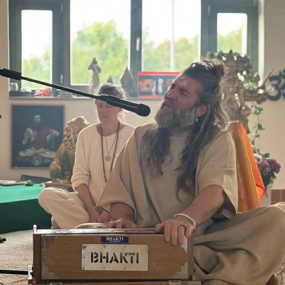 A wooden bhakti harmonium with a light brown finish and silver metal accents.