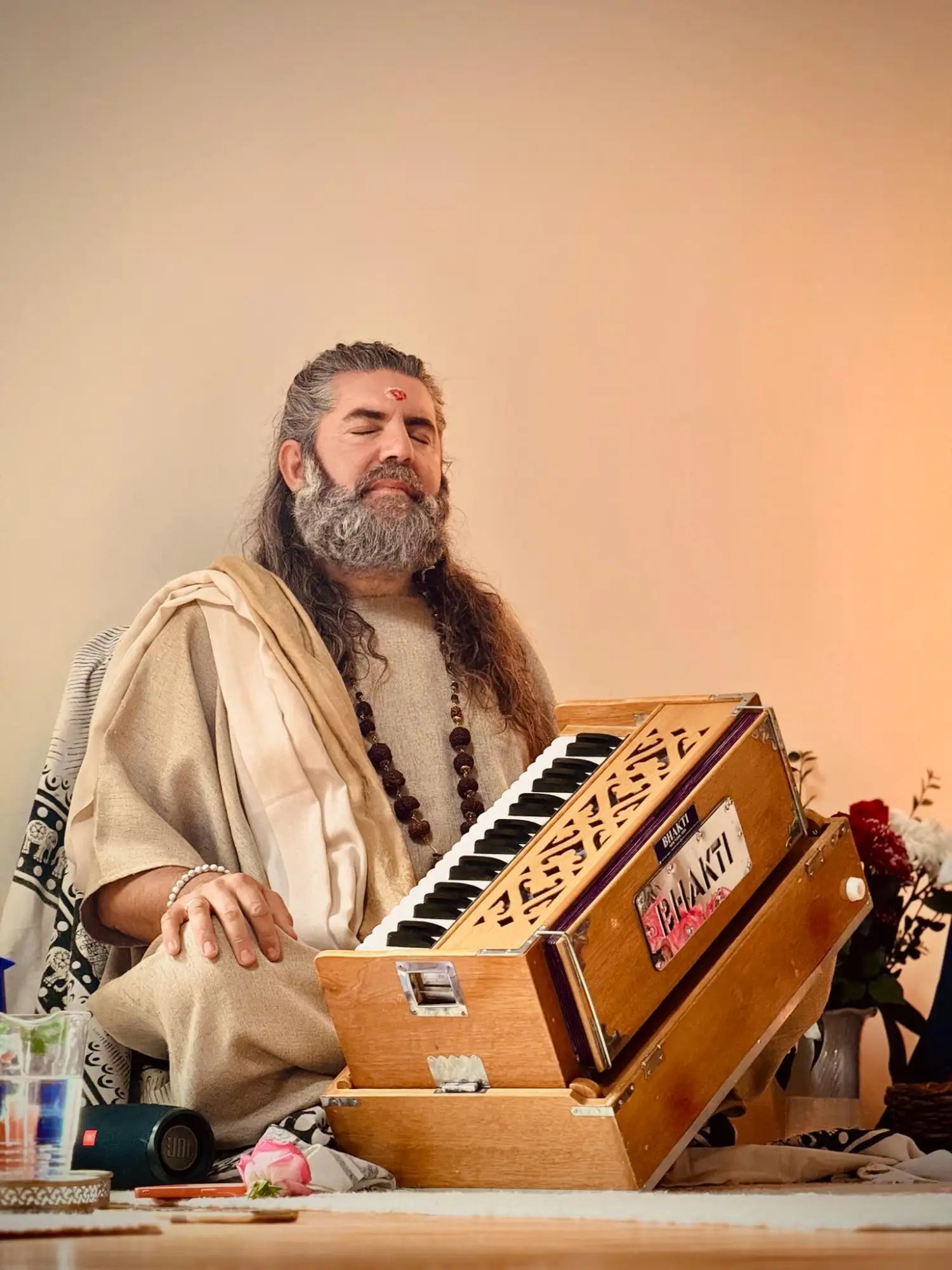A wooden harmonium with black and white keys, featuring intricate carvings on its side panels.