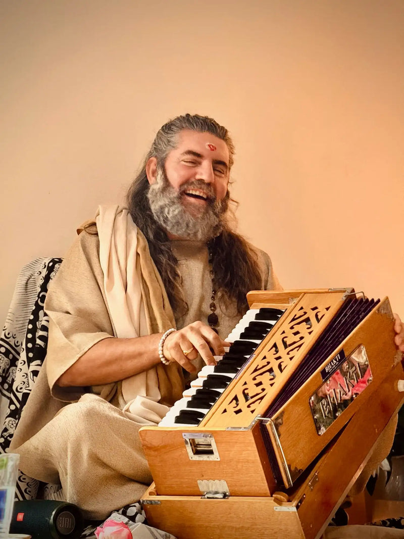 Wooden harmonium with intricate carvings and black-and-white keys, featuring a visible ’bollywood’ label on its side.