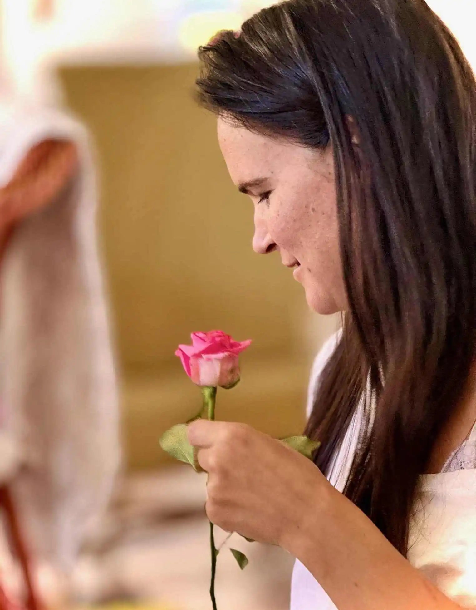 A young woman holding a single pink rose.